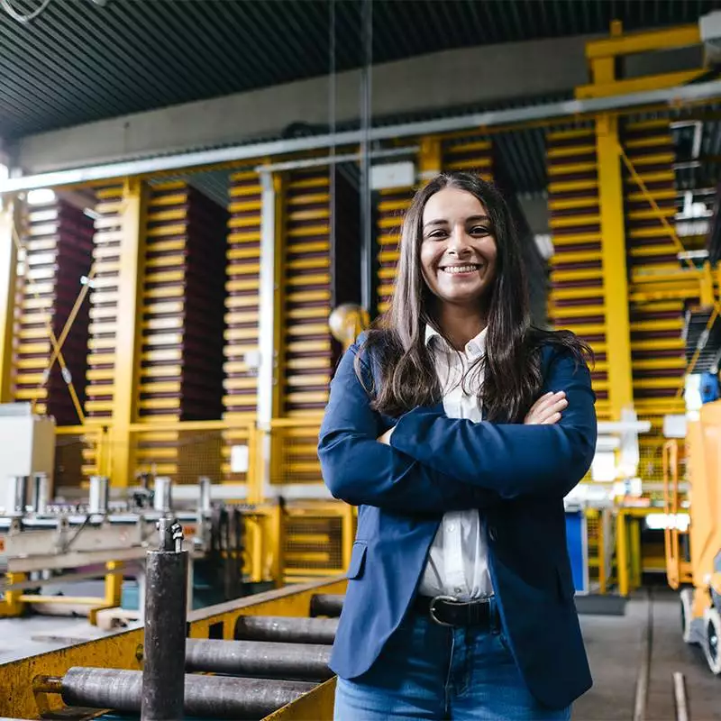 Confident woman standing in logistics center, with arms crossed